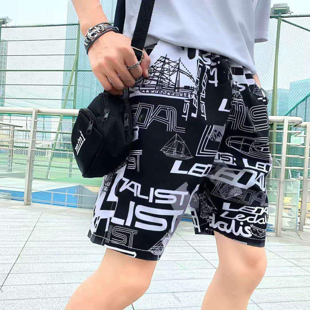 Men's beach shorts with bold black and white graphic print, offering a loose fit for comfort and style at the beach or pool.