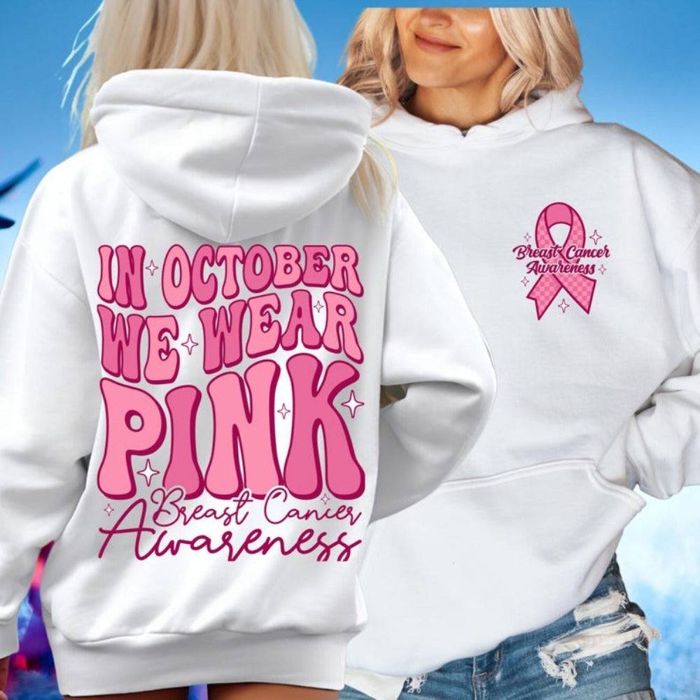 White polyester hoodie with 'In October We Wear Pink' retro print and breast cancer ribbon logo, ideal for Breast Cancer Awareness month.
