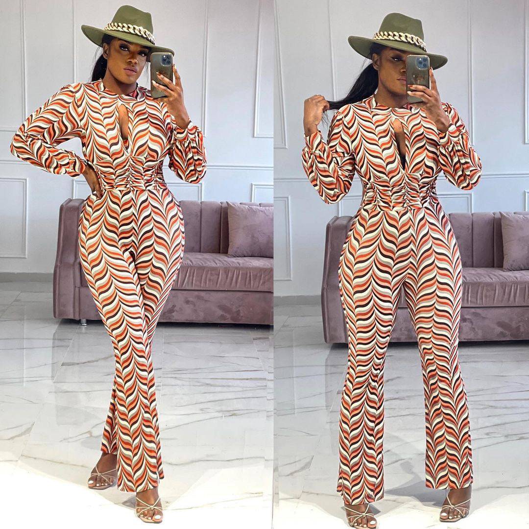Smocked Print Flared Jumpsuit with cutout nipped waist in red and white chevron pattern, styled with heels and a hat for a chic look.
