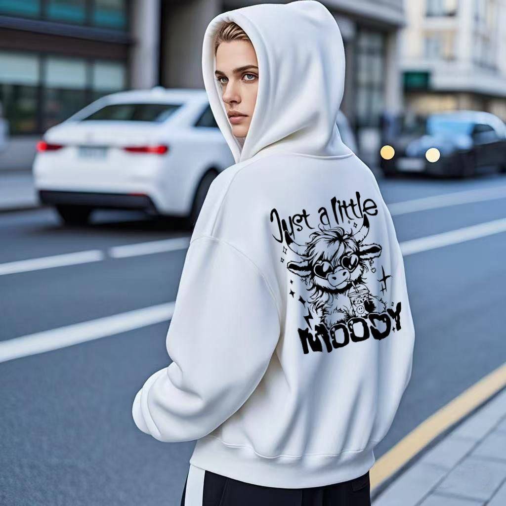 White casual fashion hoodie for men and women featuring 'Just a Little Moody' cow print, styled for urban streetwear appeal.