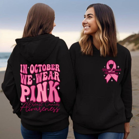 Black hoodie with bright pink breast cancer awareness ribbon and 'In October We Wear Pink' slogan, stylish support apparel for October.