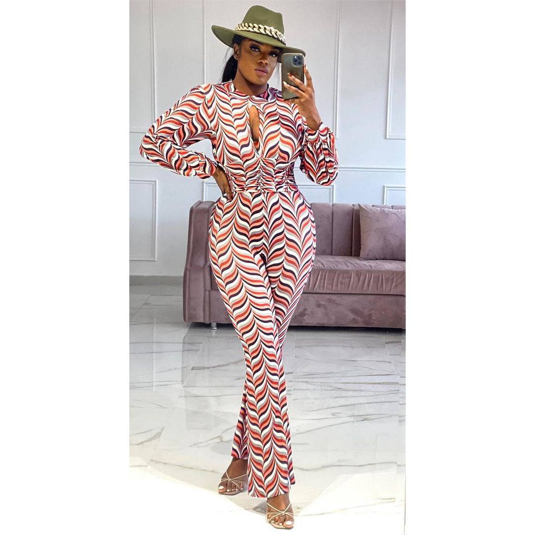 Model wearing Smocked Print Flared Jumpsuit with cutout nipped waist, posing indoors to showcase the flattering high waist and flared silhouette.