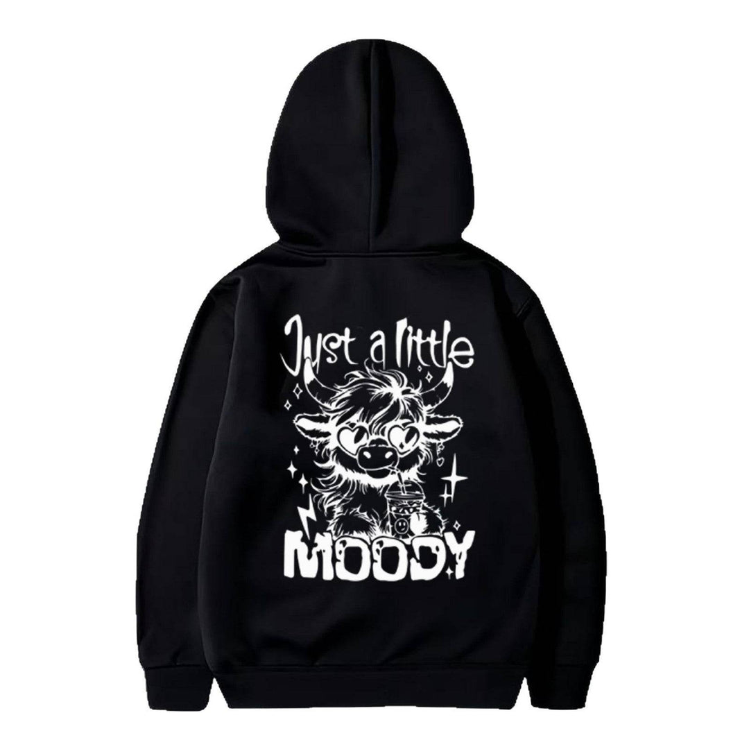 Black unisex hoodie with bold white 'Just a Little Moody' cartoon cow graphic, ideal for casual American fashion trends.